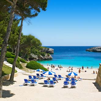 Zandstrand met ligbedden Cala d'Or Mallorca in blauwe baai